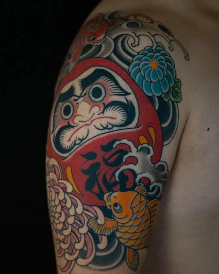 Hình xăm Daruma bắp tay phối hoa cúc rực rỡ