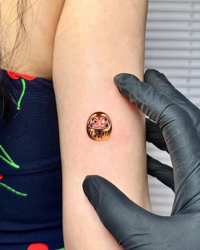 Hình xăm Daruma mini nhỏ xinh trên bắp tay nữ