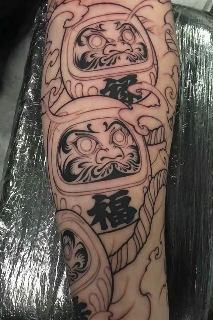 Khung hình xăm Daruma chồng lên nhau kín bắp tay