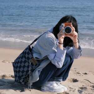 Avatar nữ che mặt cầm máy ảnh trên bãi biển