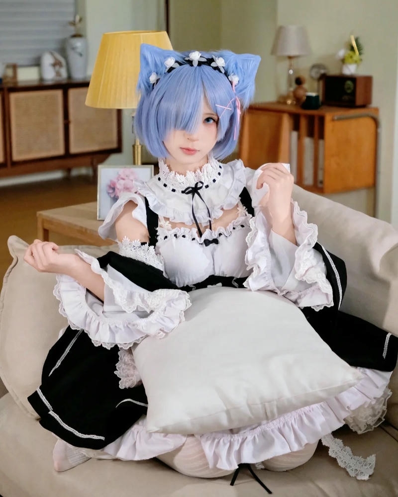 Cosplay mèo hầu gái tóc xanh ngồi trên thảm trắng