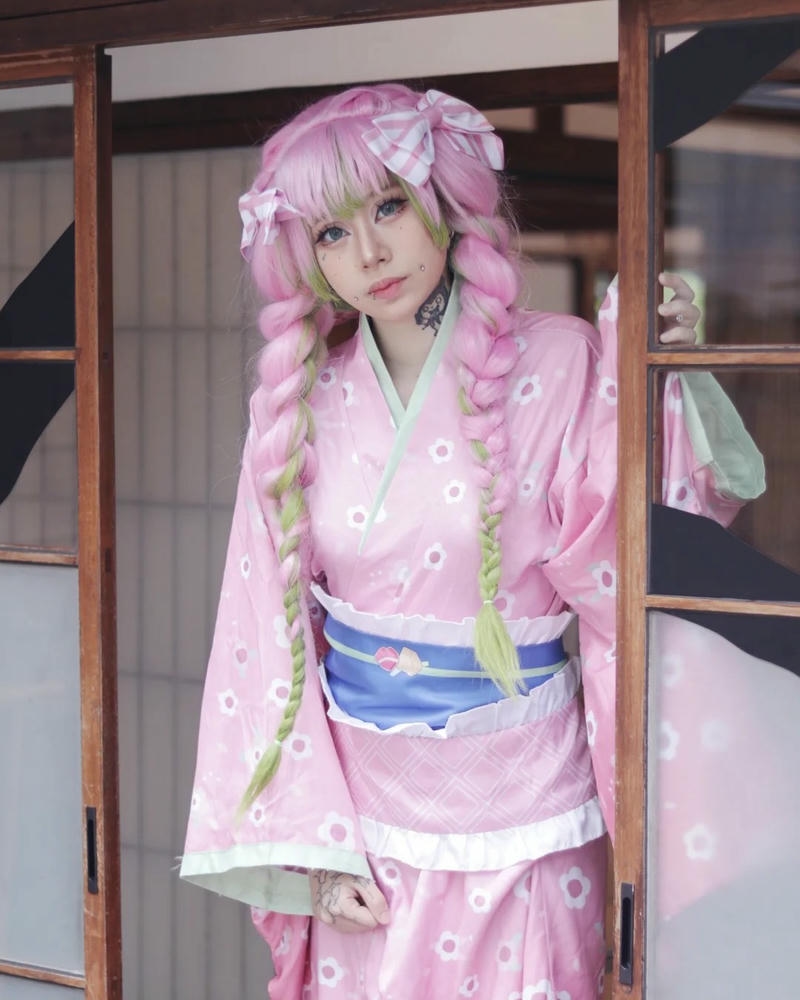 Cosplayer nữ mặc kimono hồng đứng bên cửa kéo gỗ