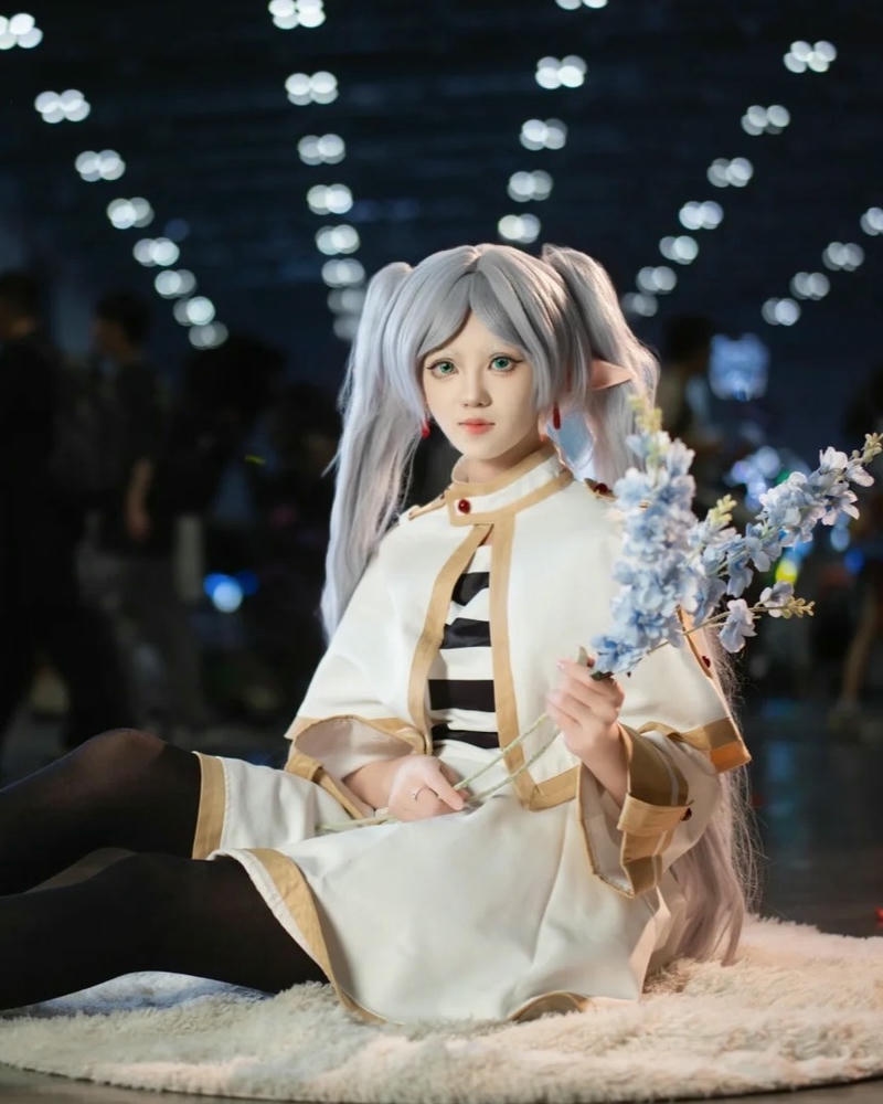 Hình Frieren cầm trượng đỏ đứng trước gương soi