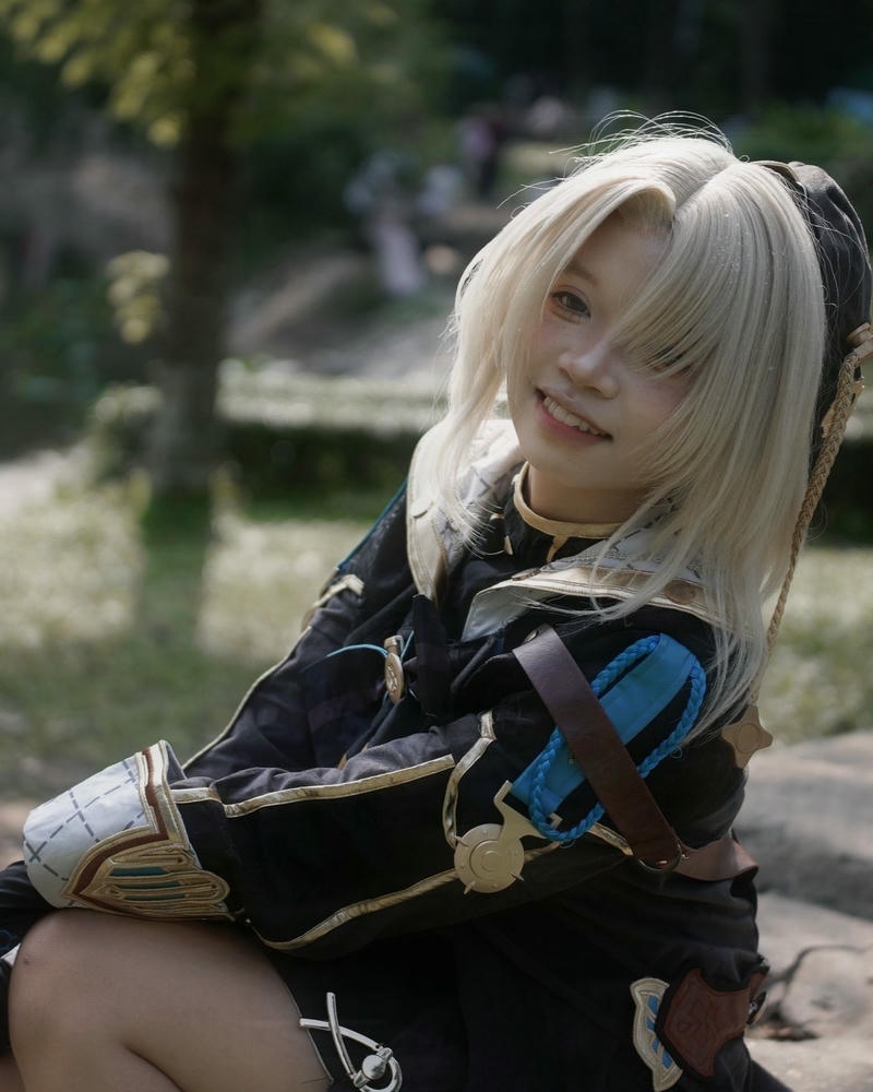 Ảnh cosplay anime nữ tóc vàng váy đen ngồi ngoài trời
