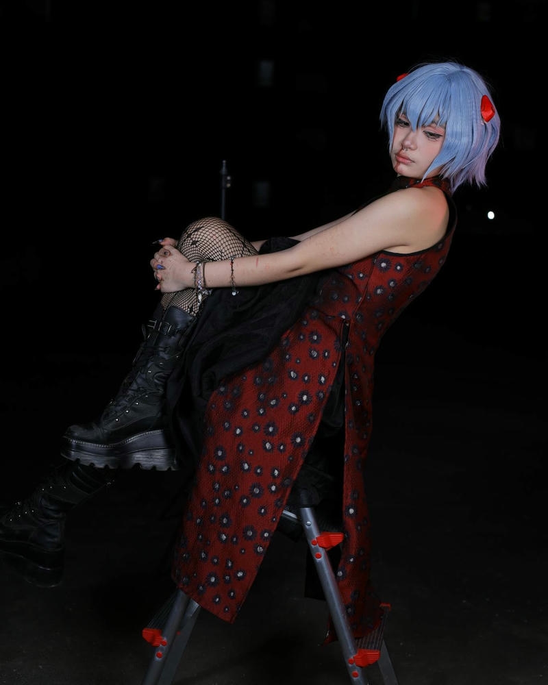 Cosplay nhân vật anime nữ tóc xanh ngồi ghế đỏ ngầu