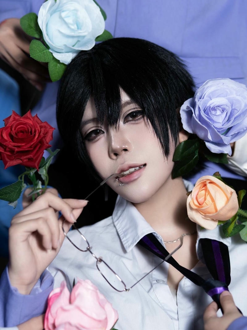 Cosplayer nam tóc đen bên hoa hồng xanh nền xanh