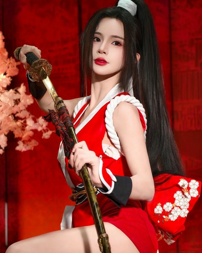 Mai Shiranui cosplay cầm dù đỏ đứng tạo dáng ngoài trời