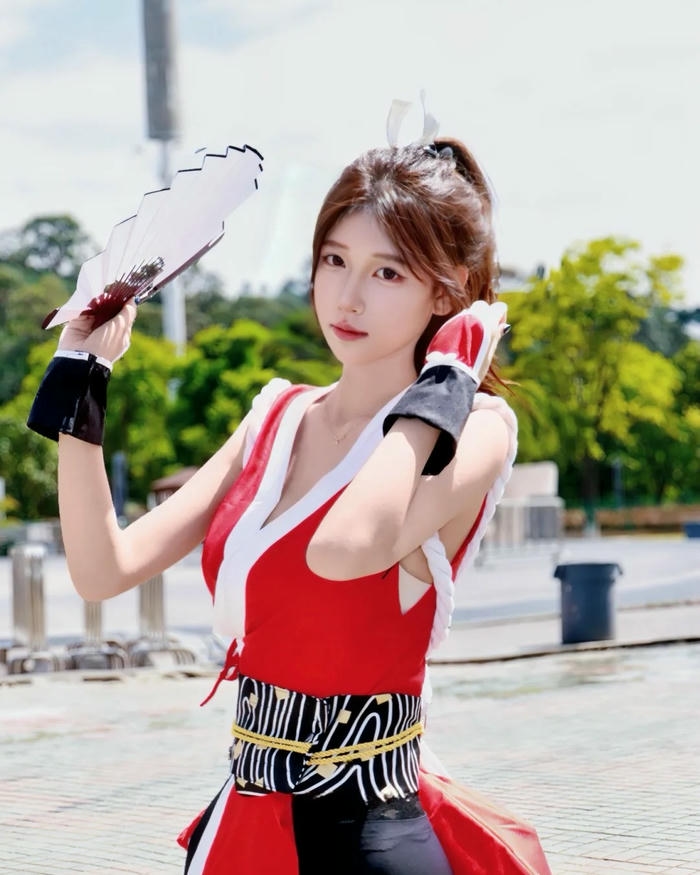 Mai Shiranui cosplay cầm quạt trắng đứng dưới trời nắng đẹp