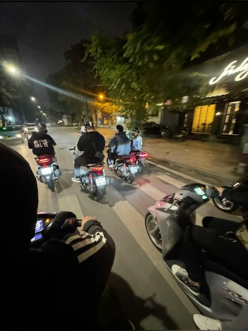 Chàng trai mặc đồ cá tính ngồi trên xe máy giữa phố đông người