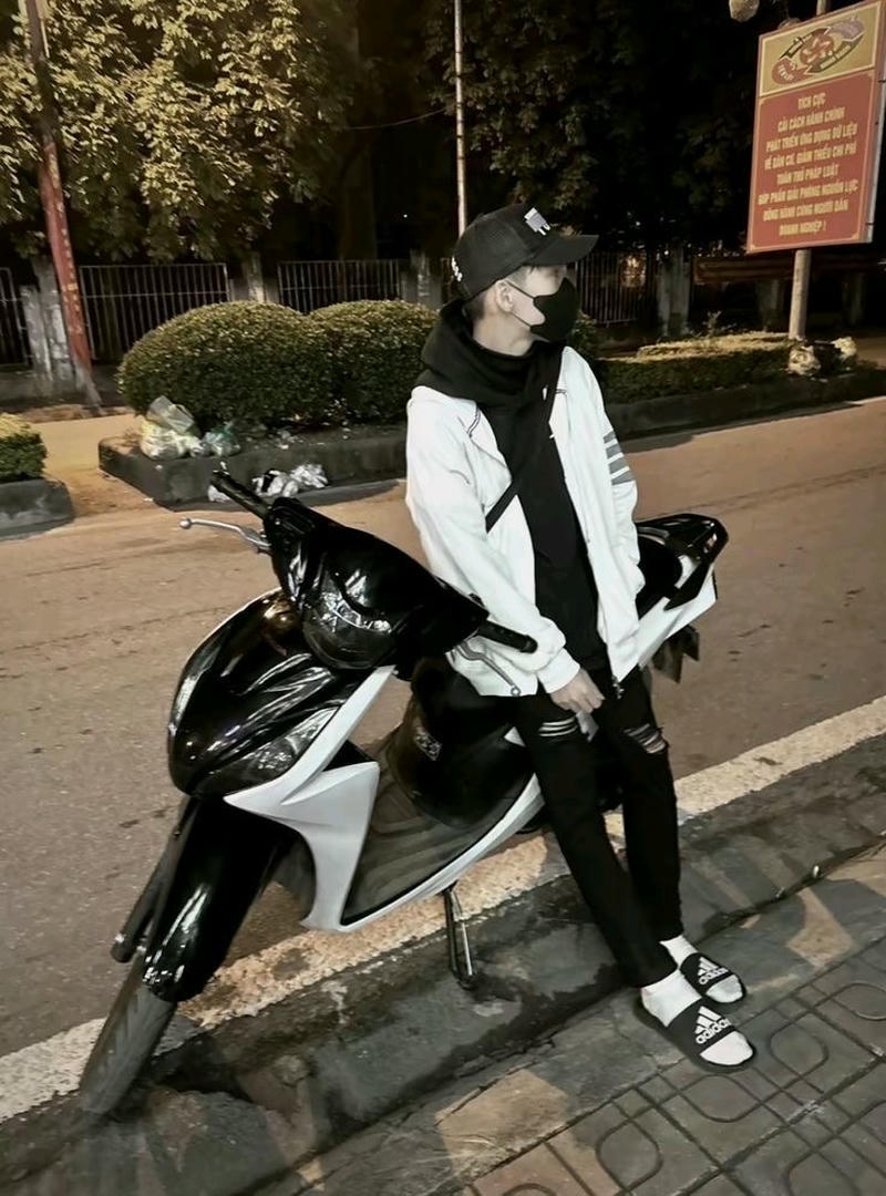 Chàng trai ngồi trên xe máy giữa đường phố mang phong cách boy phố