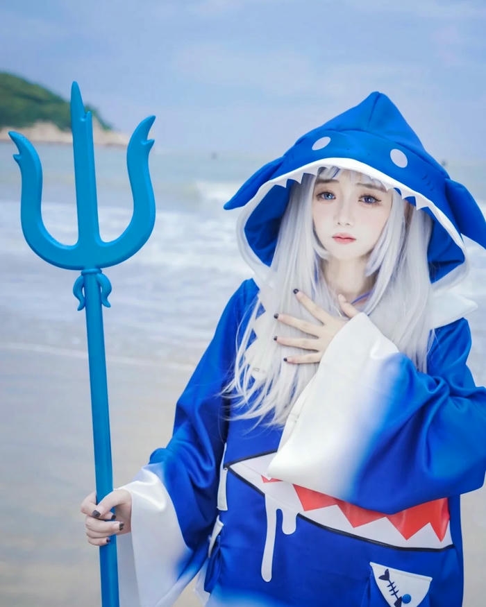 Cosplay Gura đứng cầm vũ khí trước biển xanh rộng